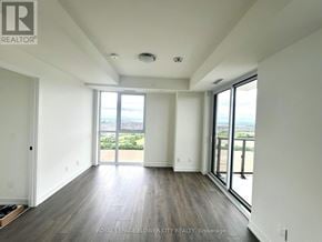 Oakville (Jm Joshua Meadows) condo for rent - A spacious room with wooden floors and large windows overlooking a view.