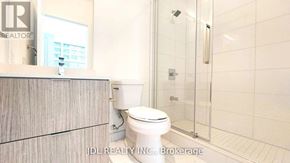 Toronto (North St. James Town) condo for rent - A white toilet in a bathroom with a glass shower door.