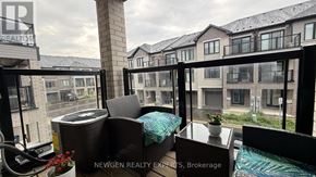 Brantford townhouse for rent - A balcony with a table and chairs overlooking a row of houses.