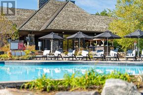 Gravenhurst (Muskoka (S)) condo for rent - A pool area with a building and umbrella tables.