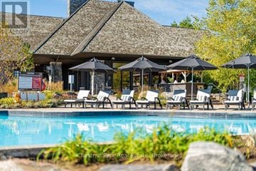 Gravenhurst (Muskoka (S)) condo for rent - A pool area with a building and umbrella tables.