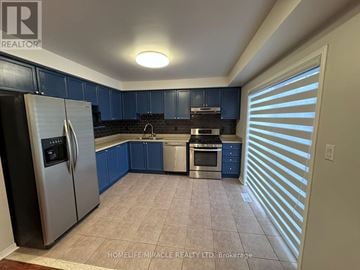 Whitby (Brooklin) apartment for rent - A kitchen with blue cabinets and a stainless steel refrigerator.