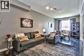 Oakville (Wm Westmount) townhouse for rent - A living room with a grey couch and a painting of a flower on the wall.