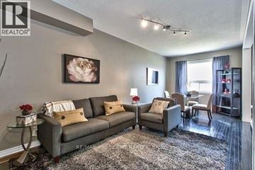 Oakville (Wm Westmount) townhouse for rent - A living room with a grey couch and a painting of a flower on the wall.