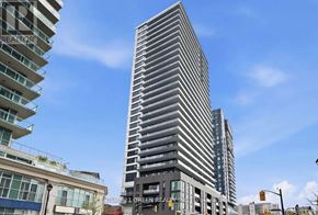 Burlington (Brant) condo for rent - A tall, modern building with a glass facade stands in the foreground of a city street.