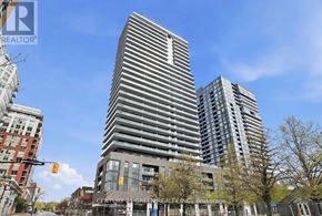 Burlington (Brant) condo for rent - A tall building with a grey facade stands in the foreground of a city street.
