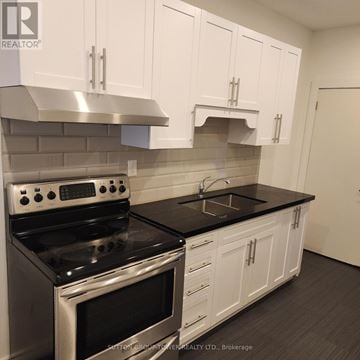 Toronto (Dovercourt-Wallace Emerson-Junction) apartment for rent - A kitchen with white cabinets and a black countertop.