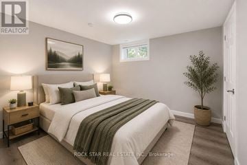 Brantford apartment for rent - A bedroom with a large bed and a potted plant.