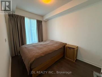 Toronto (Waterfront Communities) condo for rent - A bedroom with a bed, a window with curtains, and a wooden crate on the floor.