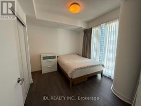 Toronto (Waterfront Communities) condo for rent - A bedroom with a bed, nightstand, and window with curtains.