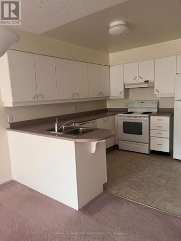 Barrie (Letitia Heights) condo for rent - A kitchen with white cabinets and a white fridge.