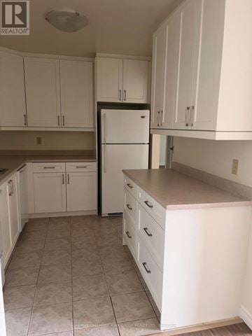 Barrie (Letitia Heights) condo for rent - A kitchen with white cabinets and a white refrigerator.