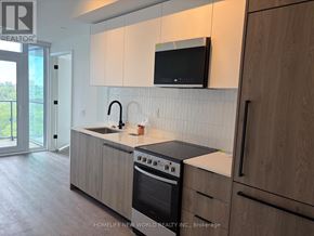 Toronto (Centennial Scarborough) condo for rent - A modern kitchen with wooden cabinets and a black microwave above the stove.