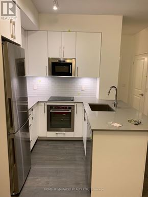 Vaughan condo for rent - A kitchen with white cabinets and a stainless steel refrigerator.