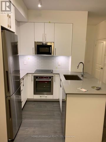 Vaughan condo for rent - A kitchen with white cabinets and a stainless steel refrigerator.