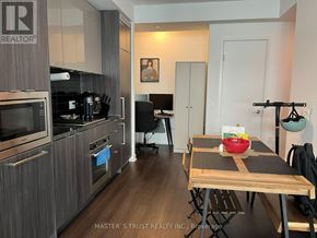 Toronto (Waterfront Communities) condo for rent - A kitchen with a wooden table and a bowl of fruit on it.