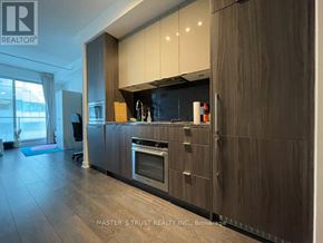 Toronto (Waterfront Communities) condo for rent - A modern kitchen with dark wood cabinets and a stainless steel oven.
