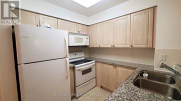 Toronto (Mimico) condo for rent - A kitchen with a white refrigerator, microwave, and stove top oven.