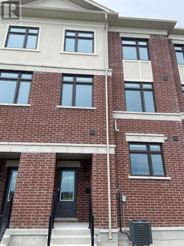 Richmond Hill townhouse for rent - A red brick building with a black door and windows.