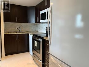 Mississauga (Mississauga Valleys) condo for rent - A kitchen with a white fridge, black oven, and brown cabinets.
