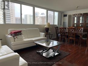 Mississauga (Mississauga Valleys) condo for rent - A white couch with a red pillow is in the middle of a room with a glass table and chairs.