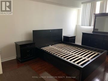 Mississauga (Mississauga Valleys) condo for rent - A bedroom with a black bed and wooden floors.