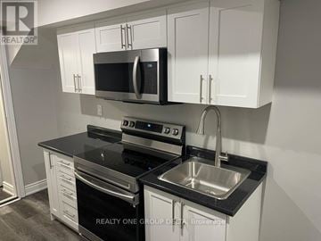 Brampton (Bram West) apartment for rent - A kitchen with white cabinets and black countertops.