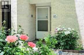 Toronto (St. Andrew-Windfields) townhouse for rent - A white door with the number 85 on it is flanked by pink and white flowers.