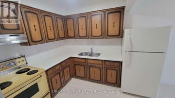 Toronto (Hillcrest Village) townhouse for rent - A kitchen with wooden cabinets and a white refrigerator.