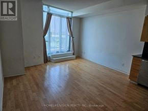 Toronto (Niagara) condo for rent - A room with wooden flooring and a window with curtains.