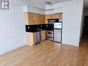 Toronto (Niagara) condo for rent - A kitchen with wooden cabinets and black countertops.