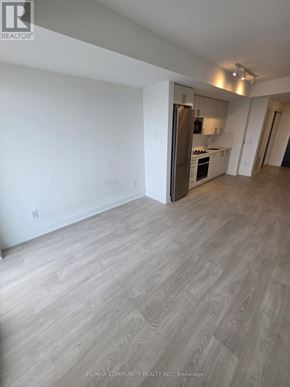 Oshawa (Windfields) condo for rent - A spacious room with a kitchen area in the background.