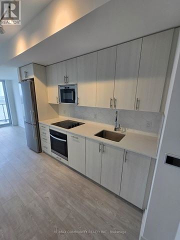 Oshawa (Windfields) condo for rent - A kitchen with white cabinets and a grey floor.