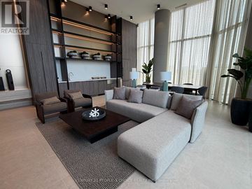 Vaughan (Steeles West Industrial) condo for rent - A modern living room with a grey sofa, a coffee table, and a large window.