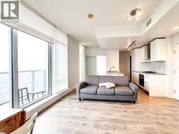 Vancouver apartment for rent - A living room with a grey couch and a dining table.