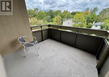Ottawa condo for rent - A balcony with a chair and a view of trees.
