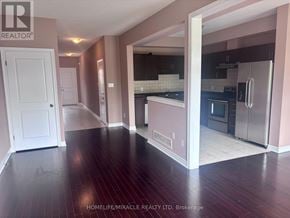 Hamilton (Lakeshore) townhouse for rent - A realtor photo of an empty house with a kitchen in the background.