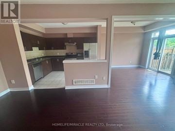 Hamilton (Lakeshore) townhouse for rent - A realtor photo of a kitchen and living room with wood floors.