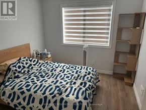 Belleville (Thurlow Ward) townhouse for rent - A bedroom with a bed covered in a blue and white patterned comforter.