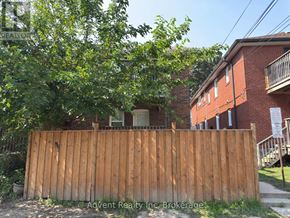 Toronto (Lawrence Park South) duplex for rent - A wooden fence in front of a red brick building.
