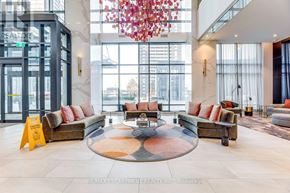Toronto (Islington-City Centre West) condo for rent - A large, modern lobby with a circular coffee table at the center and a chandelier hanging from the ceiling.