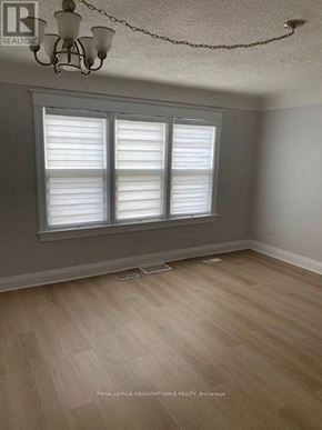 Hamilton (Stipley) triplex for rent - A room with a chandelier, a window with white blinds, and wooden flooring.