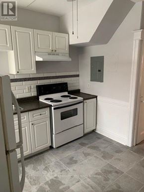 Hamilton (Stipley) triplex for rent - A kitchen with white cabinets and a black countertop.