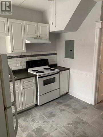 Hamilton (Stipley) triplex for rent - A kitchen with white cabinets and a black countertop.
