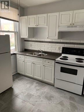Hamilton (Stipley) triplex for rent - A kitchen with white cabinets and a black stove top oven.