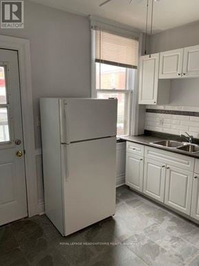 Hamilton (Stipley) triplex for rent - A white refrigerator in a kitchen with white cabinets and a white door.