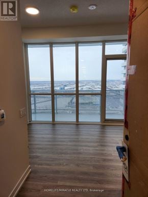 Vaughan (Vaughan Corporate Centre) condo for rent - A view of a city from a large window in a room with wooden floors and white walls.
