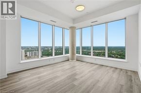 Kitchener condo for rent - A spacious room with large windows overlooking a cityscape.