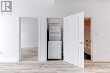 Hamilton (Waterdown) condo for rent - A white kitchen with a refrigerator, oven, and microwave in a room with white walls and wooden flooring.