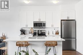 Ottawa townhouse for rent - A modern kitchen with white cabinets and a stainless steel refrigerator.